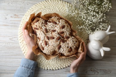 Photo of Woman with delicious Italian Easter dove cake (traditional Colomba di Pasqua) at white wooden table, top view