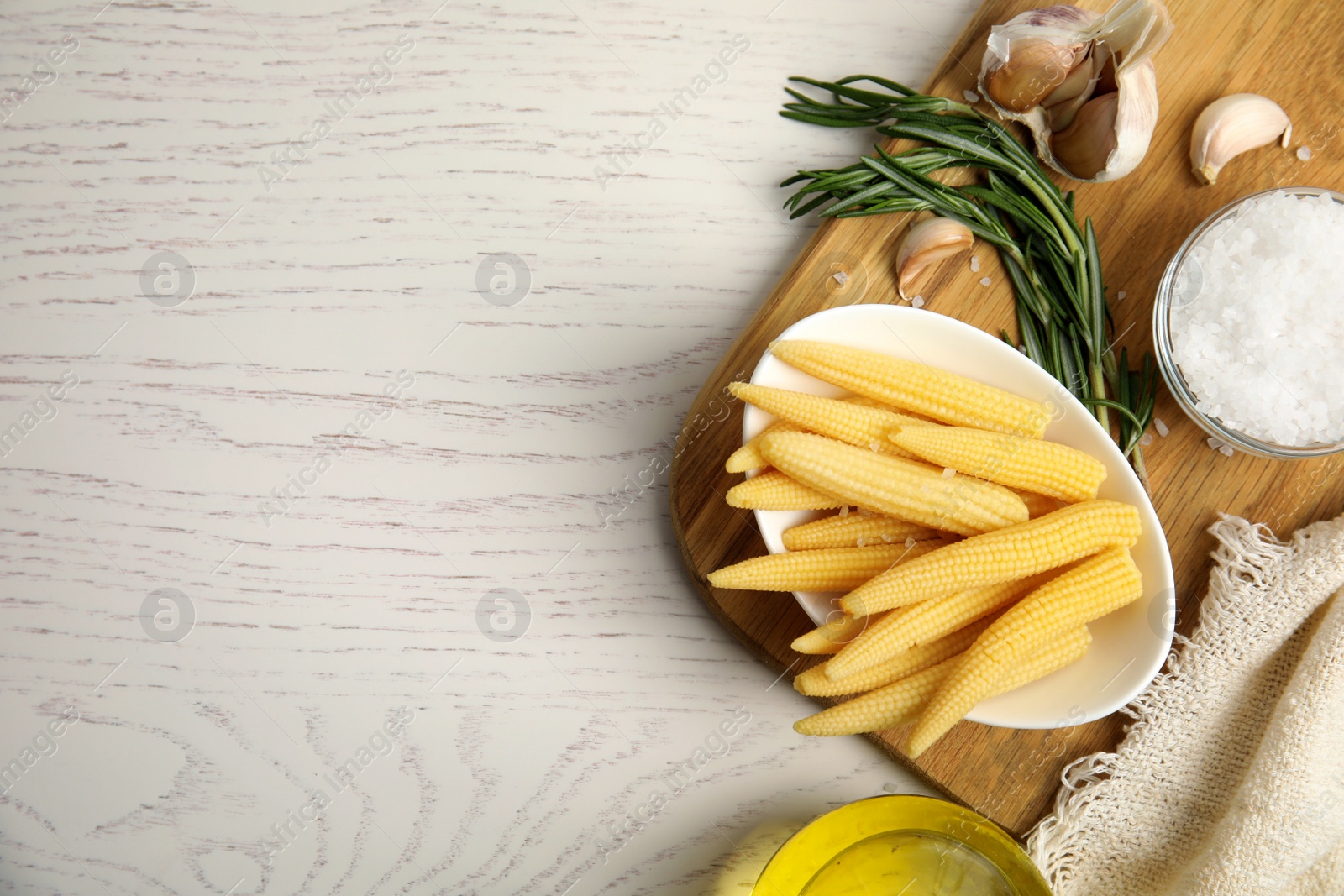 Photo of Fresh baby corn cobs and spices on white wooden table, flat lay. Space for text