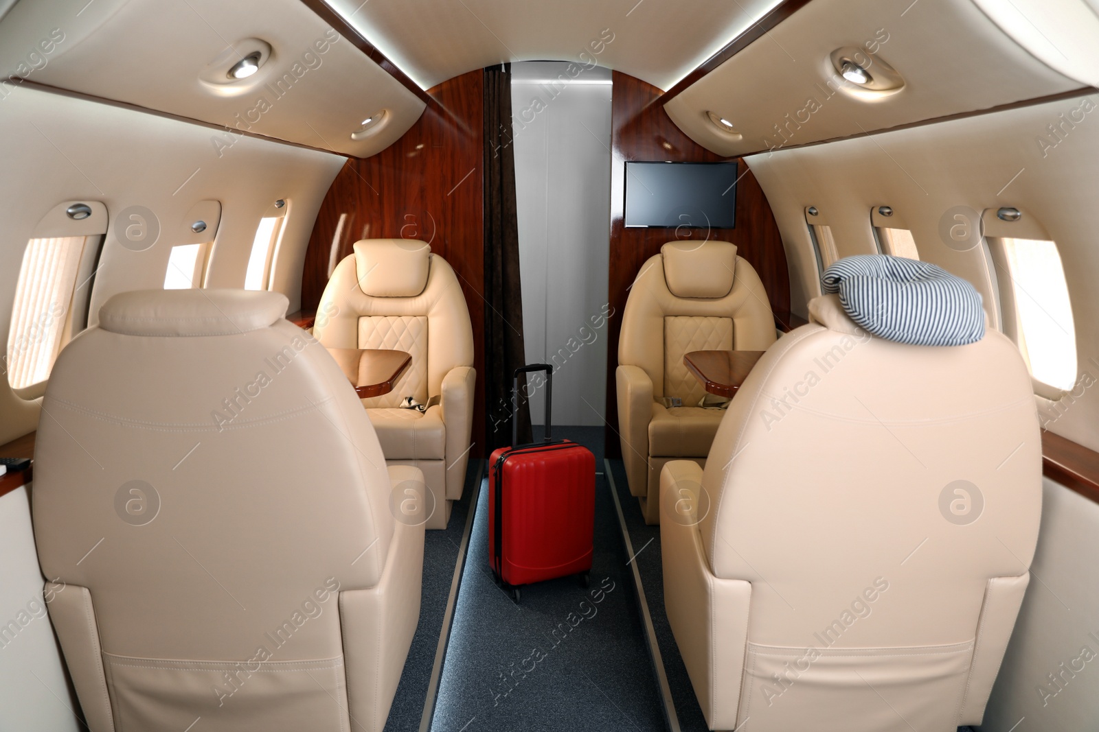 Image of Airplane cabin with red suitcase. Air travel