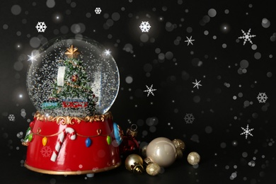 Image of Beautiful snow globe and Christmas balls on black background, space for text. Bokeh effect