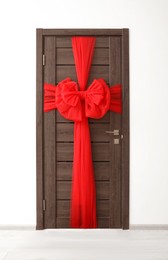 Photo of Wooden door with red beautiful bow. Christmas decoration