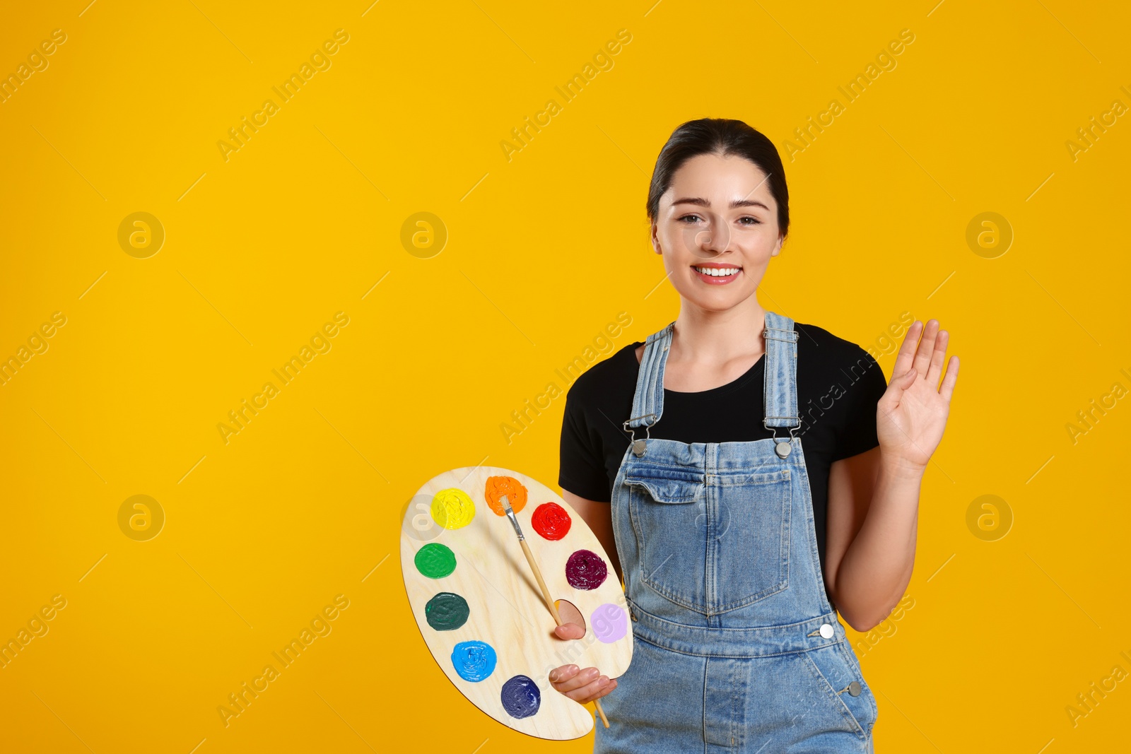 Photo of Woman with painting tools on yellow background, space for text. Young artist