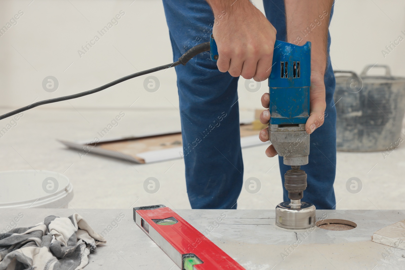 Photo of Worker making socket hole in tile indoors, closeup