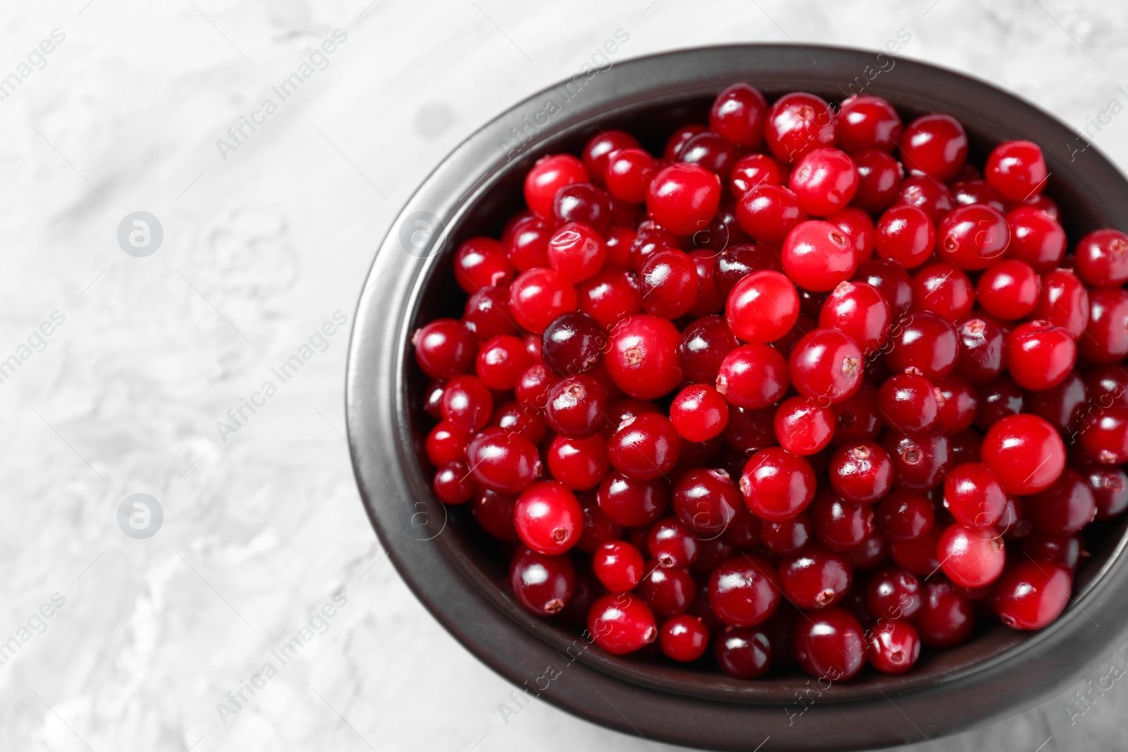 Photo of Fresh ripe cranberries in bowl on grey table, top view