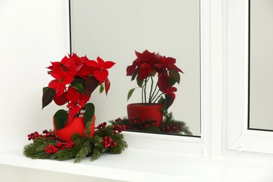 Photo of Potted poinsettia and festive decor on windowsill in room, space for text. Christmas traditional flower