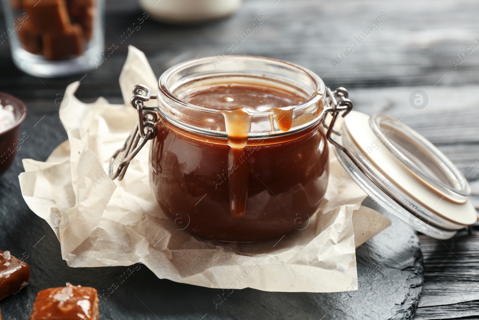 Photo of Jar with tasty caramel sauce on table