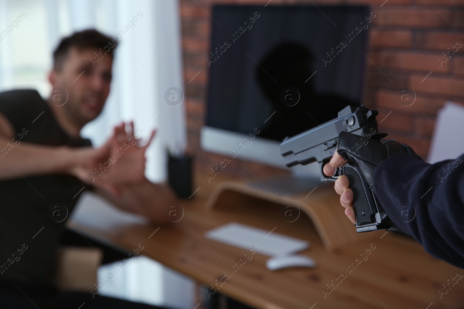 Photo of Man aiming his victim with gun indoors, closeup. Dangerous criminal