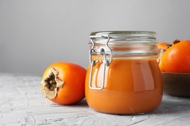 Delicious persimmon jam and fresh fruits on grey table