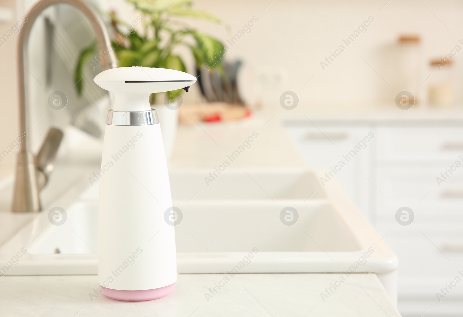 Photo of Modern automatic soap dispenser on countertop in kitchen. Space for text