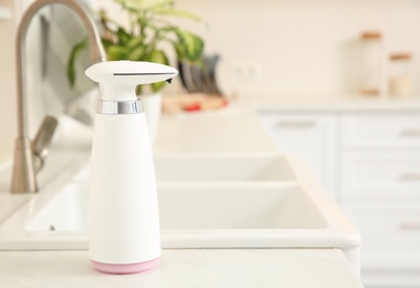 Photo of Modern automatic soap dispenser on countertop in kitchen. Space for text