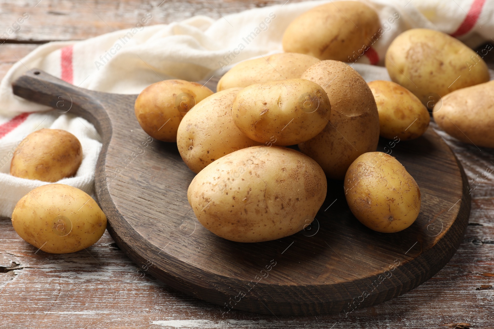 Photo of Raw fresh potatoes and cutting board on wooden table