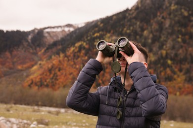 Photo of Boy looking through binoculars in beautiful mountains