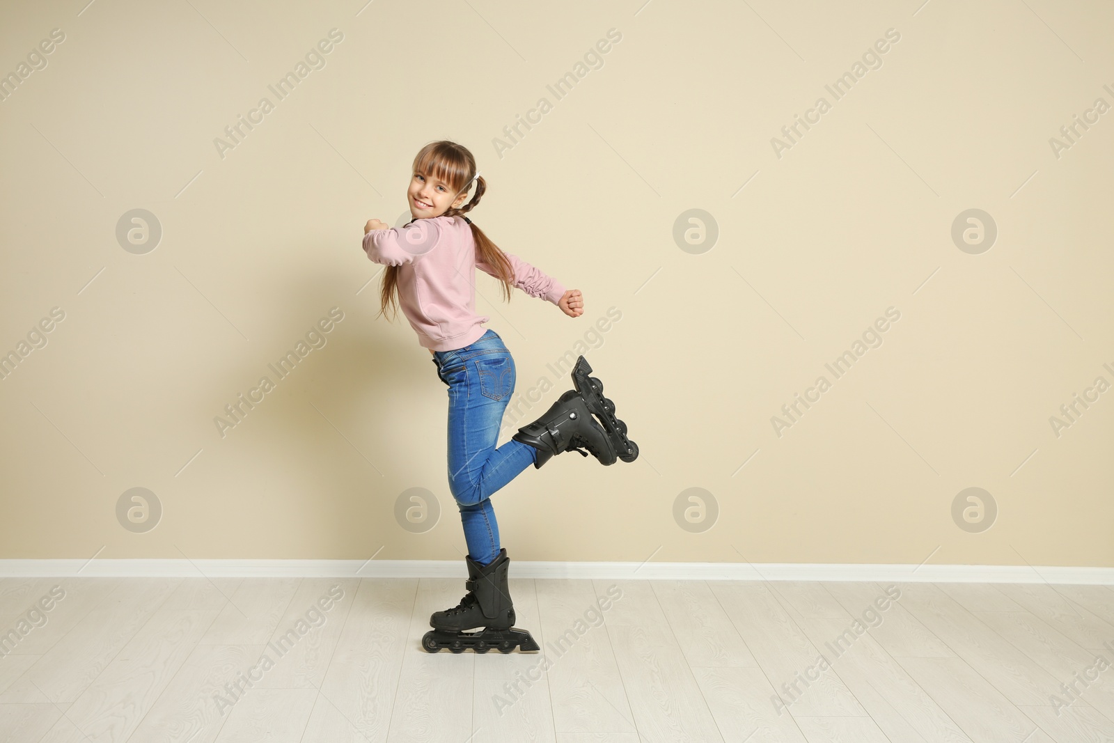 Photo of Cute girl with inline roller skates near color wall