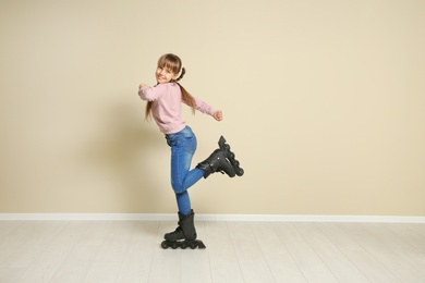 Photo of Cute girl with inline roller skates near color wall