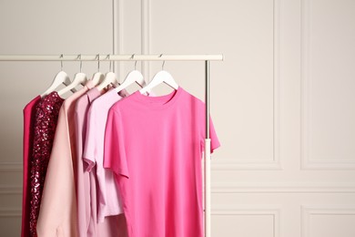 Photo of Rack with different stylish women`s clothes near white wall, space for text