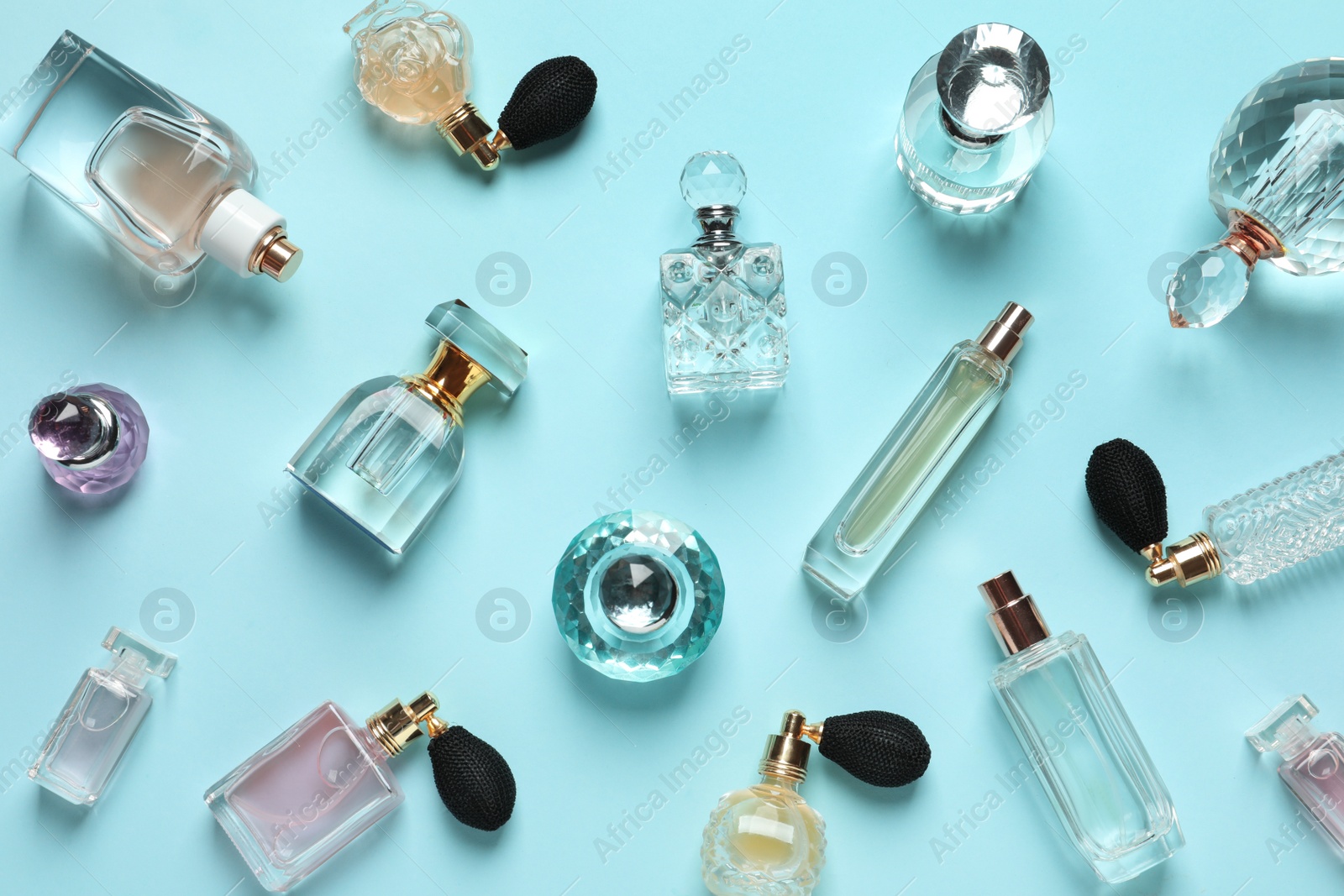 Photo of Flat lay composition with different perfume bottles on light blue background