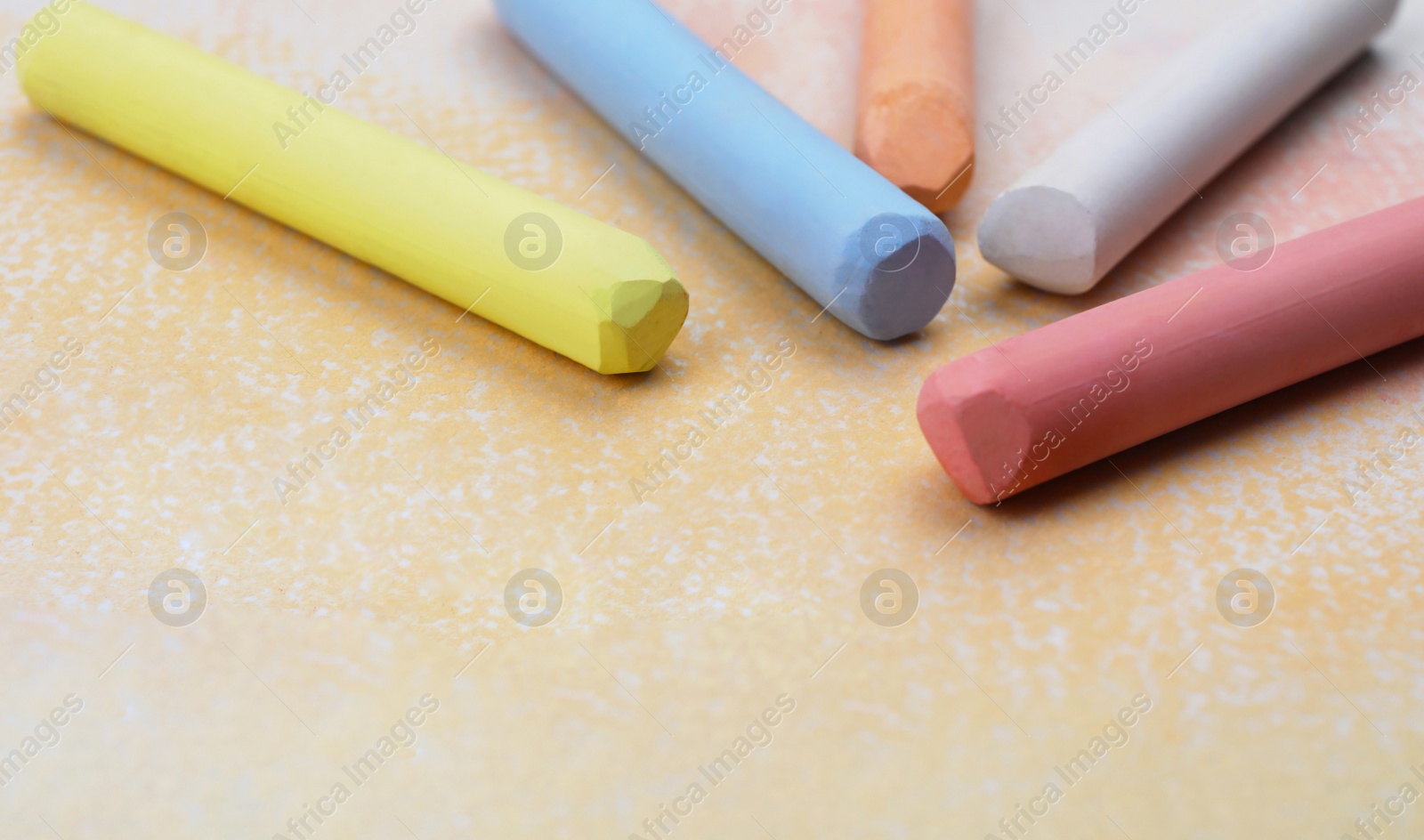 Photo of Colorful pastel chalks on abstract painting, closeup. Drawing materials