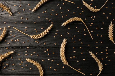 Flat lay composition with ears of wheat on black wooden table