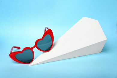 Stylish heart shaped glasses with decorative element on color background