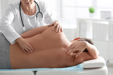 Photo of Female orthopedist examining patient's back in clinic, closeup