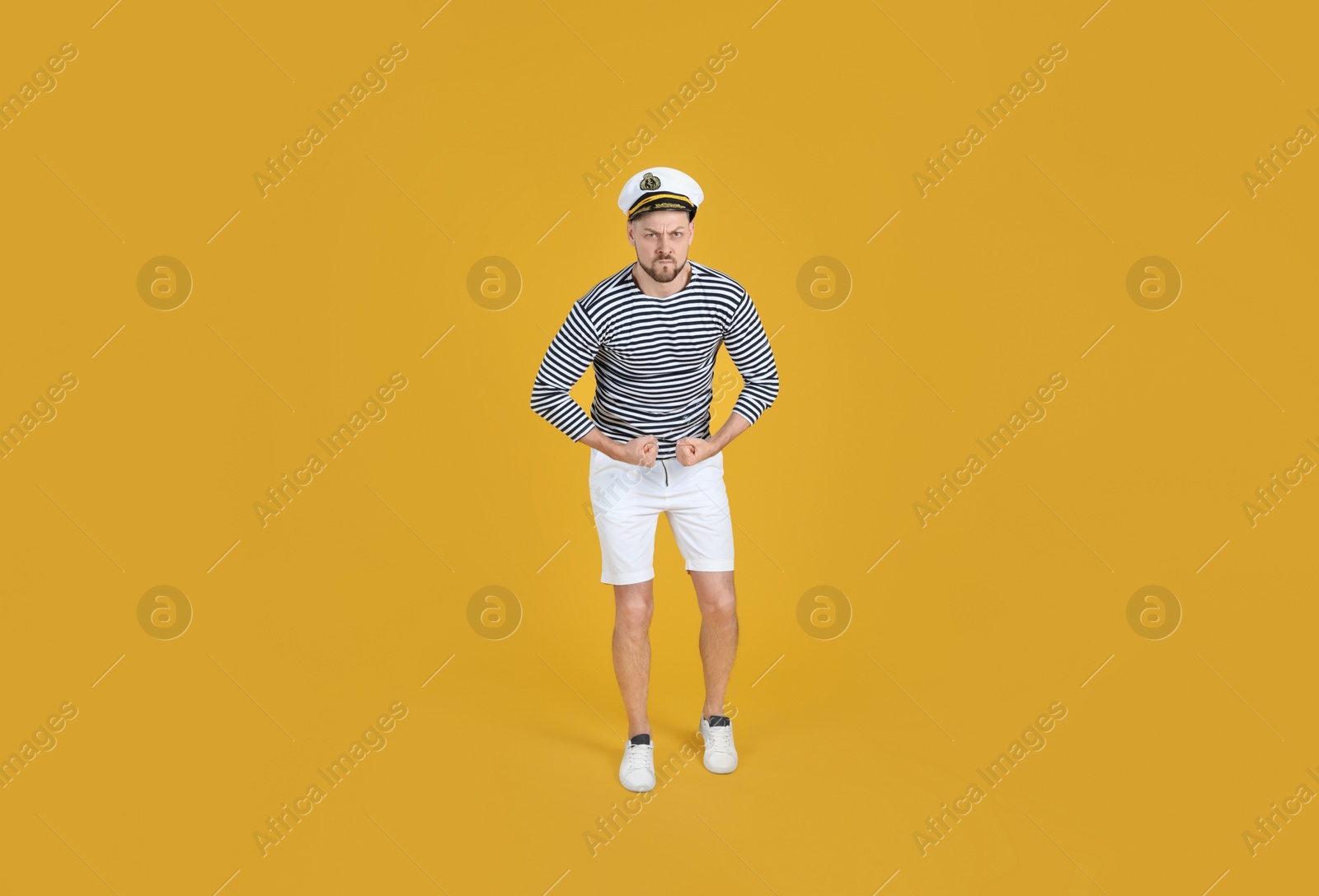 Photo of Serious sailor showing strength on yellow background