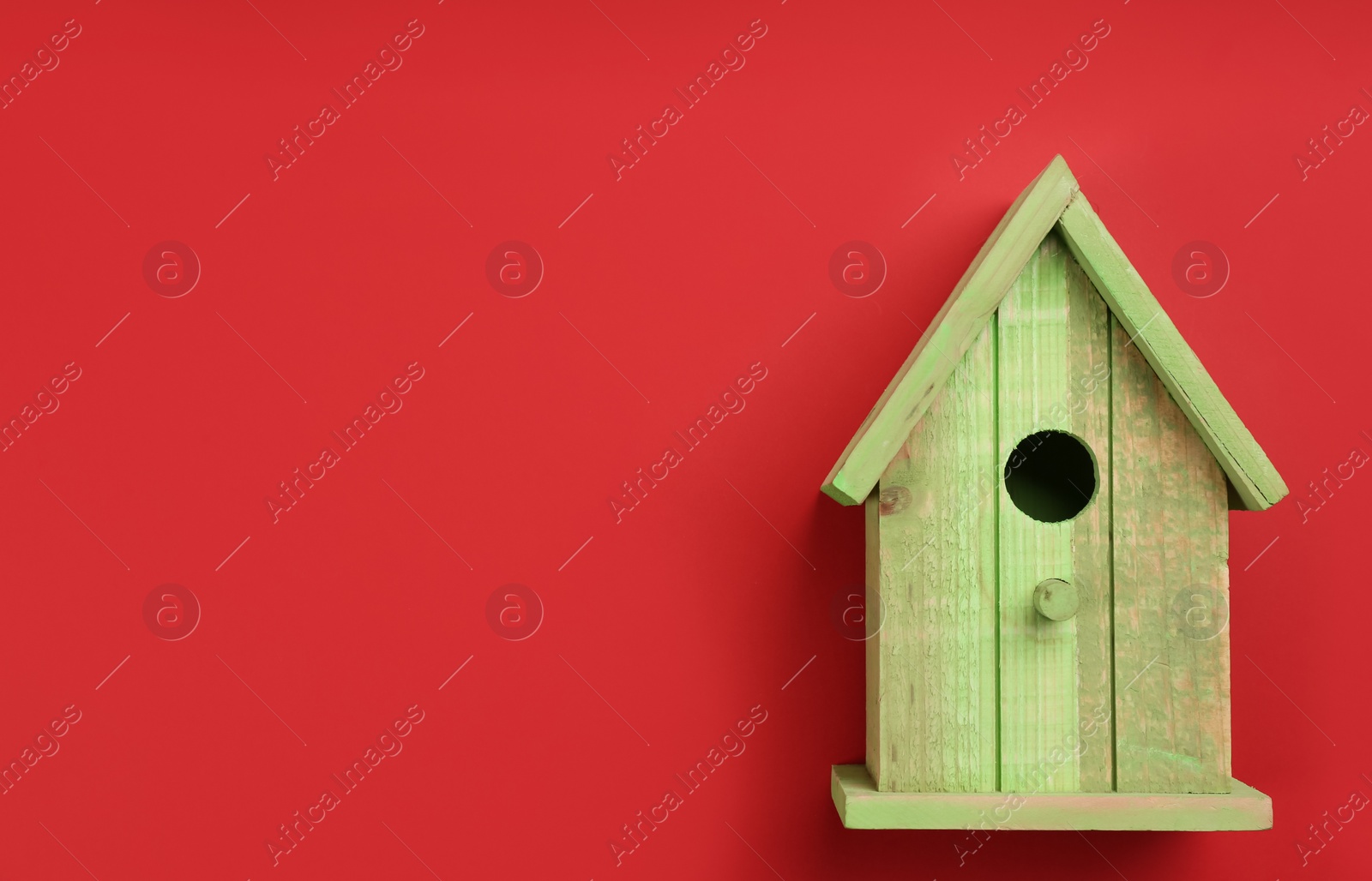 Photo of Beautiful bird house on red background, top view. Space for text