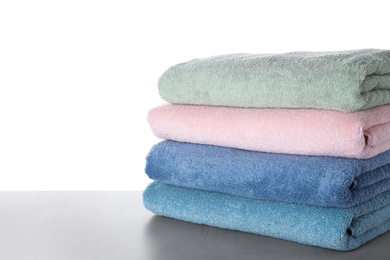 Photo of Fresh towels on light grey table against white background