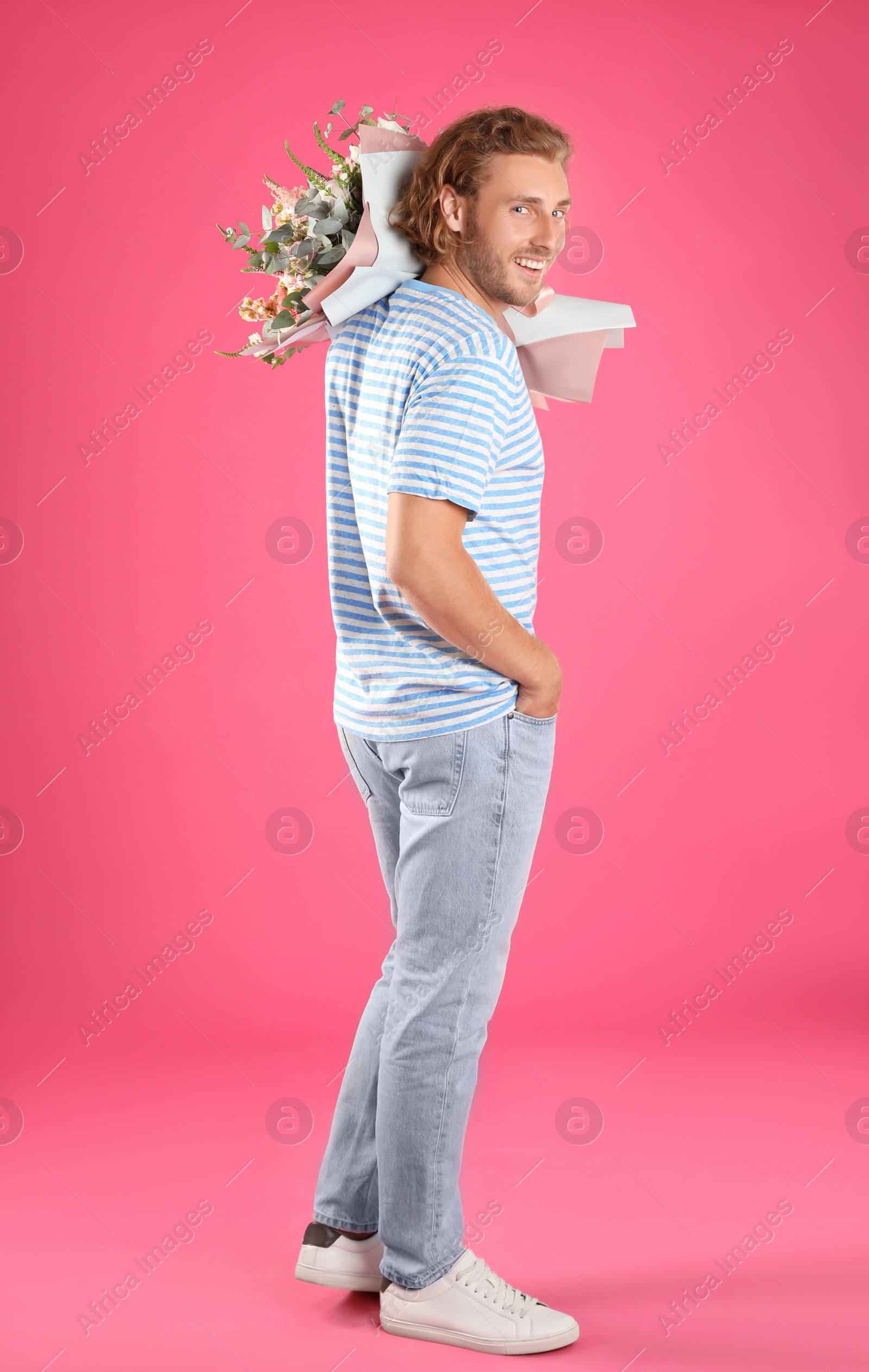 Photo of Young handsome man with beautiful flower bouquet on pink background