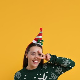 Happy young woman in Christmas sweater on orange background