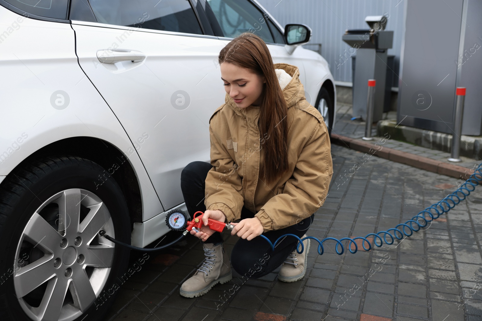 Photo of Young woman inflating tire at car service