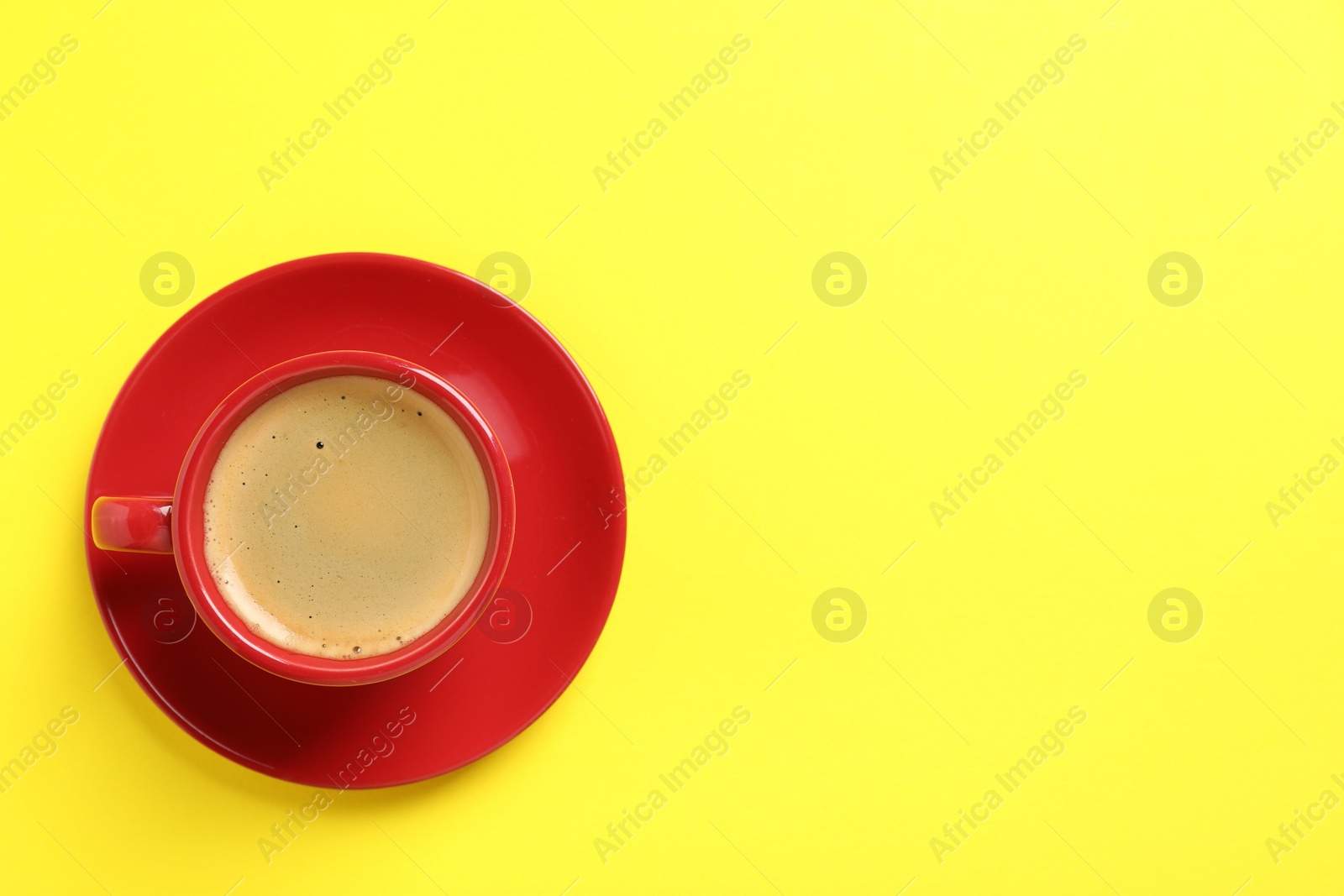 Photo of Tasty coffee in cup on yellow background, top view. Space for text