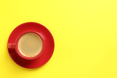 Tasty coffee in cup on yellow background, top view. Space for text