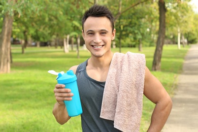 Man with bottle of protein shake in green park