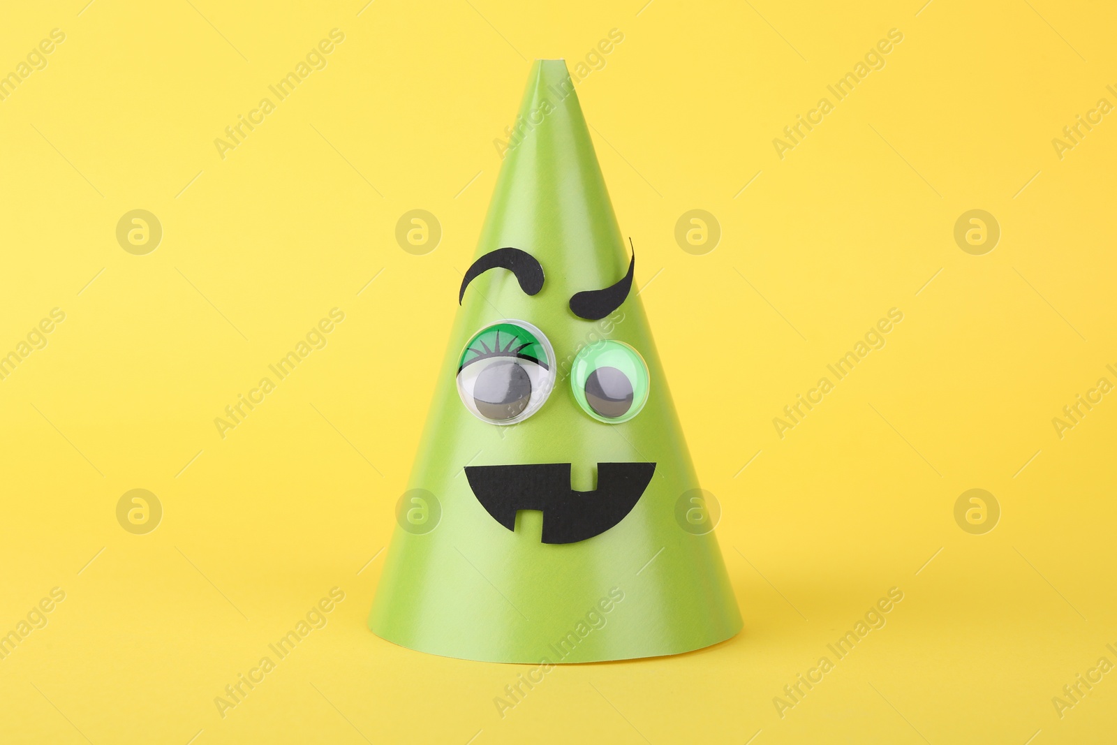 Photo of Spooky paper monster on yellow background. Halloween decoration