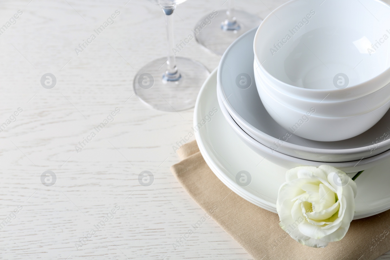 Photo of Dishware, napkin and eustoma flower on light table, closeup. Space for text