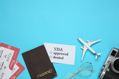 Flat lay composition with passport, toy plane and tickets on light blue background, space for text. Visa receiving