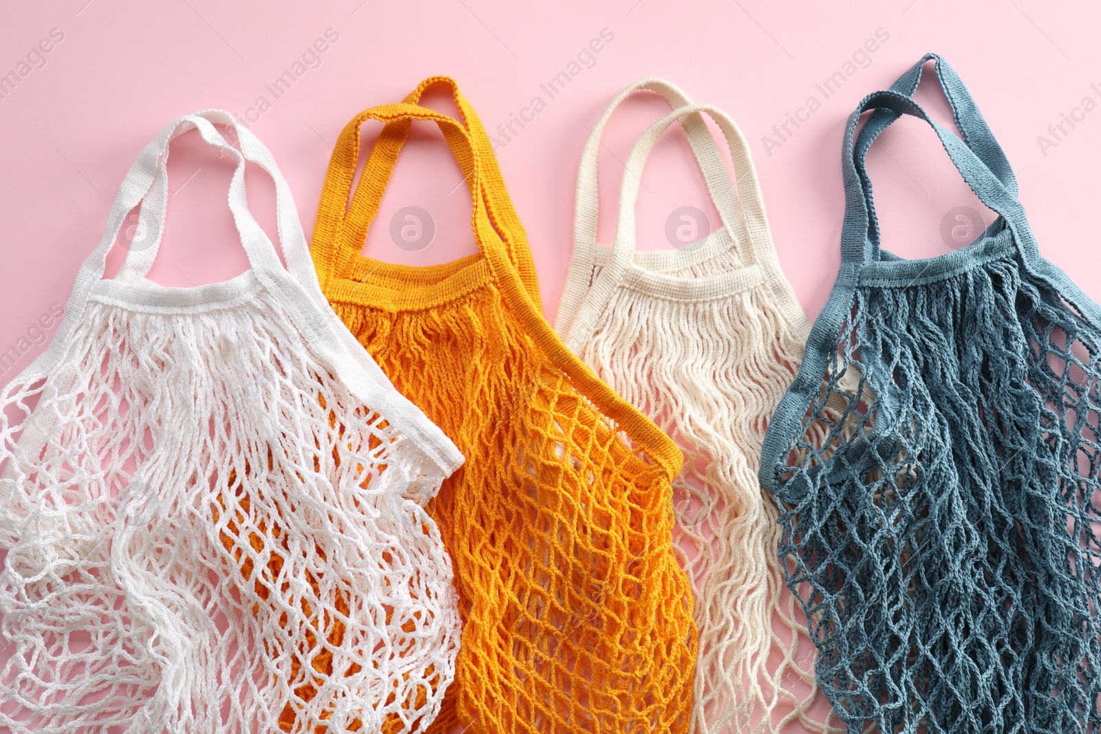 Photo of Different string bags on pink background, top view