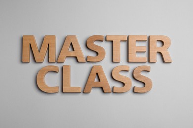 Photo of Words Master Class made of wooden letters on light grey background, flat lay