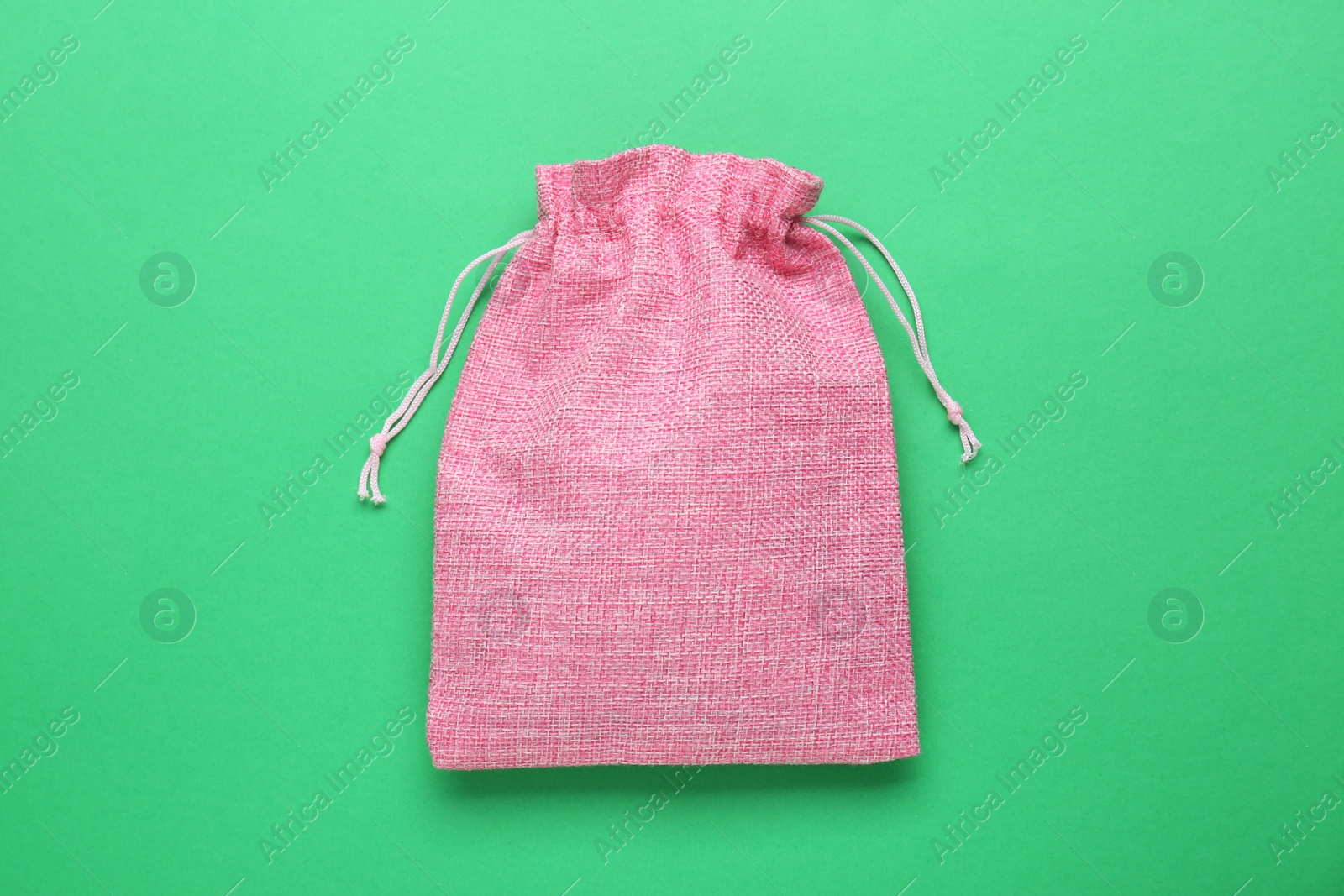 Photo of Pink burlap bag on green background, top view