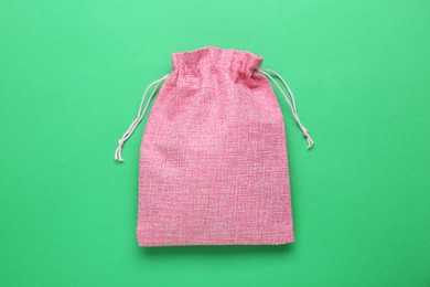 Pink burlap bag on green background, top view