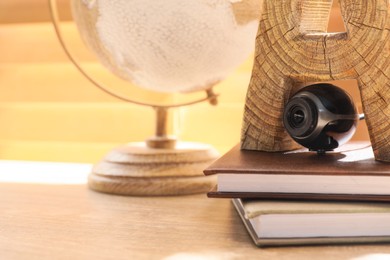 Photo of Small camera hidden among stationery on wooden desk against window indoors