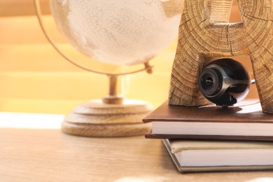 Small camera hidden among stationery on wooden desk against window indoors