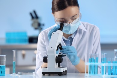 Photo of Scientist working with microscope and test tubes in laboratory