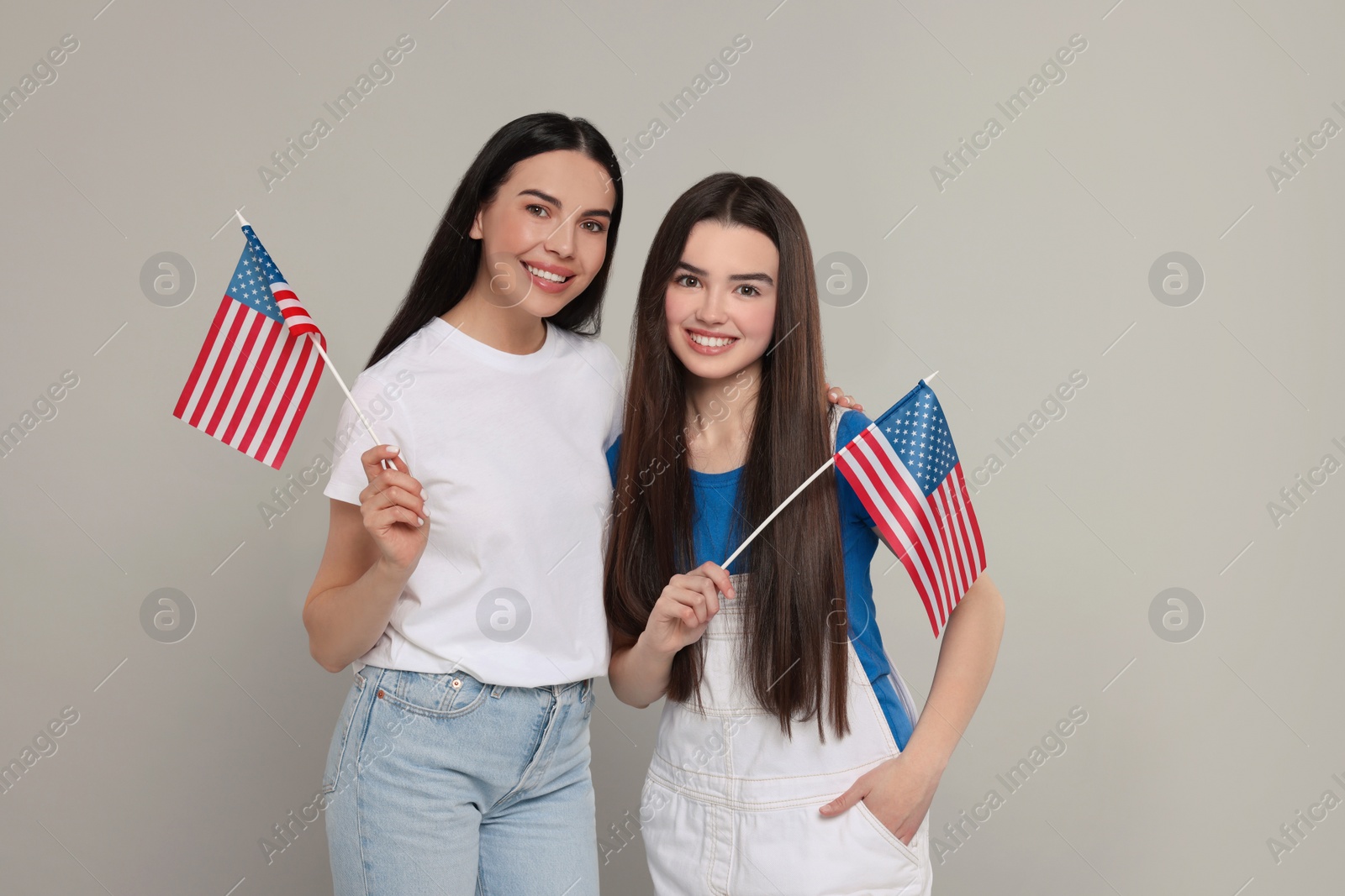 Photo of 4th of July - Independence Day of USA. Happy woman and her daughter with American flags on light grey background