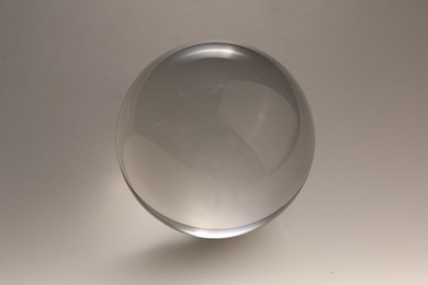 Photo of Transparent glass ball on light grey background