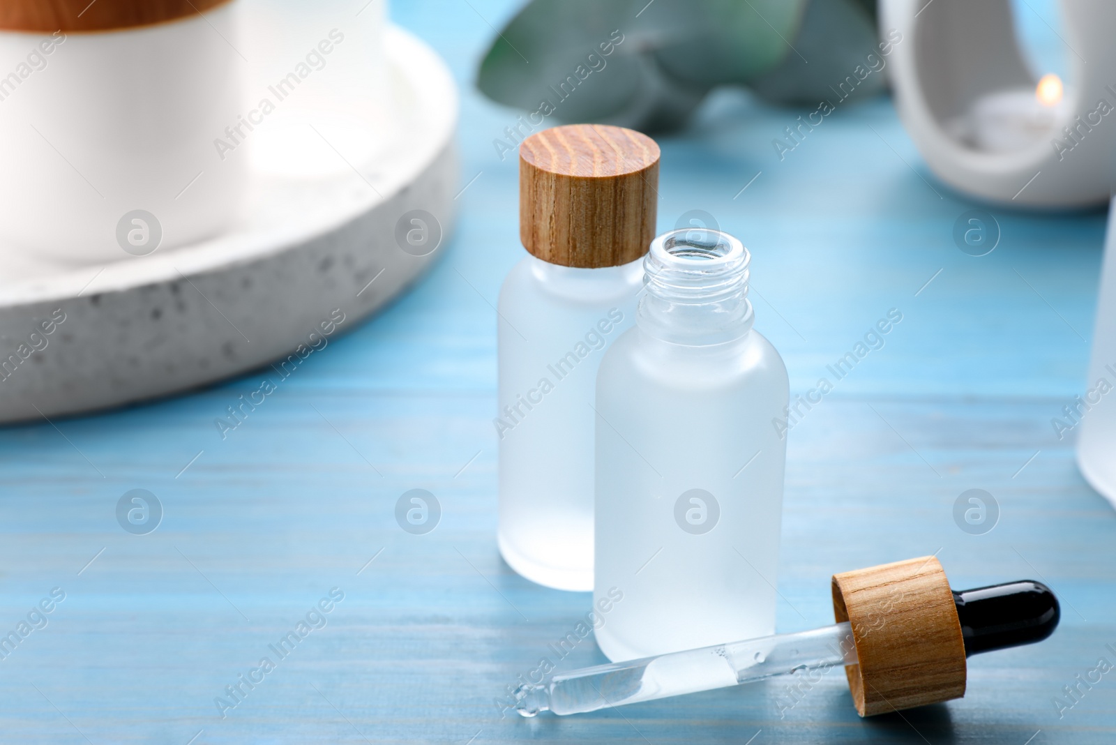 Photo of Bottles of essential oil on light blue wooden table, closeup. Space for text