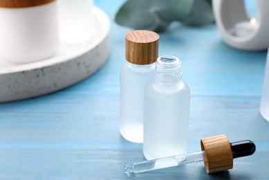 Bottles of essential oil on light blue wooden table, closeup. Space for text