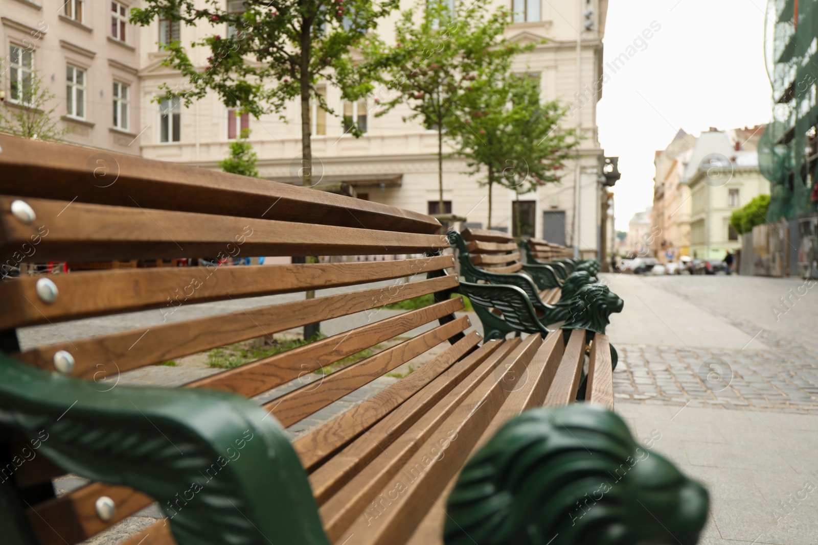 Photo of View of wooden bench with wrought legs on city street