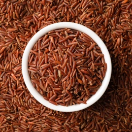 Ceramic bowl with raw brown rice on cereal, top view