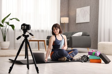 Happy sports blogger recording fitness lesson with camera at home